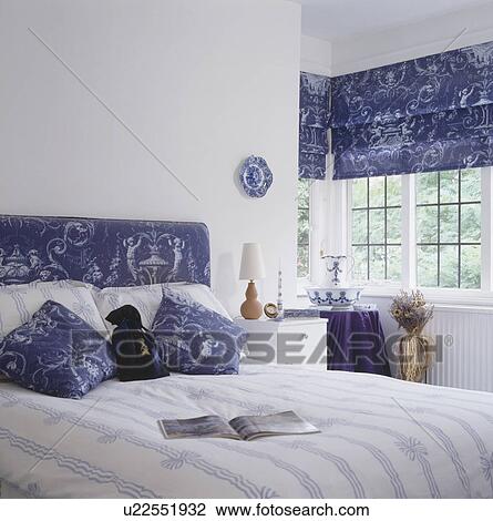 Blue & white patterned blind and matching headboard and cushions on bed in traditional white bedroom View Large Photo Image Stock Image - Blue & white patterned blind and matching headboard and cushions on bed in traditional white bedroom. Fotosearch