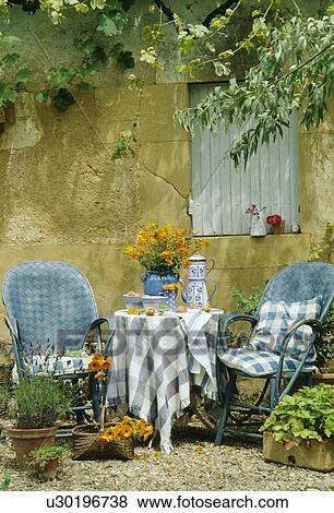 Stock Photo - Blue+white cloth and pots on table in front of old stone wall in country garden in summer. Fotosearch