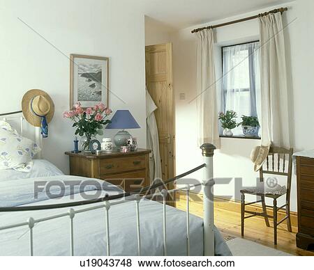 Brass bed with white linen in bedroom with cream curtains and small wooden chair View Large Photo Image Stock Photo - Brass bed with white linen in bedroom with cream curtains and small wooden chair . Fotosearch