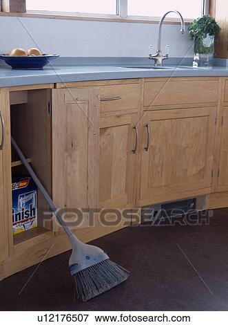 Broom and dishwasher powder in cupboard in modern pale wood kitchen View Large Photo Image Stock Photo - Broom and dishwasher powder in cupboard in modern pale wood kitchen. Fotosearch