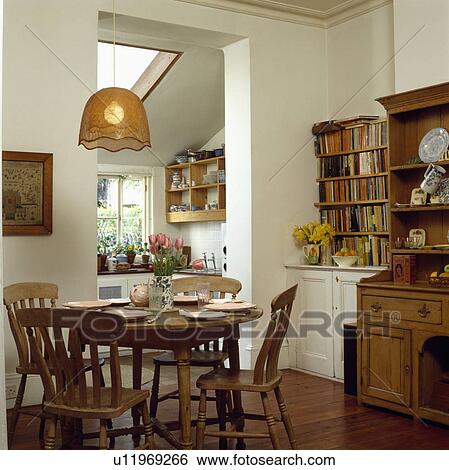 Cane Lampshade Above Circular Antique Pine Table And Chairs In