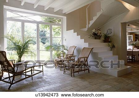 Cane loungers in white architectural hall with white modern stone staircase and patio doors and pale brick flooring View Large Photo Image Stock Image - Cane loungers in white architectural hall with white modern stone staircase and patio doors and pale brick flooring. Fotosearch