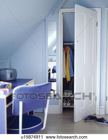 Stock Image - Child's blue bedroom with study area and built in wardrobe under the eaves of a modern attic conversion. Fotosearch
