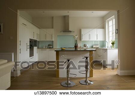 Chrome and perspex stools at breakfast bar in modern white kitchen extension with wooden flooring View Large Photo Image Stock Image - Chrome and perspex stools at breakfast bar in modern white kitchen extension with wooden flooring. Fotosearch