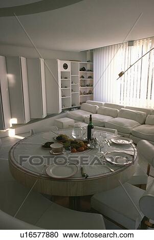 Circular table and chairs in eighties dining and living room with white sofa in front of vertical white slatted blinds View Large Photo Image Stock Image - Circular table and chairs in eighties dining and living room with white sofa in front of vertical white slatted blinds. Fotosearch
