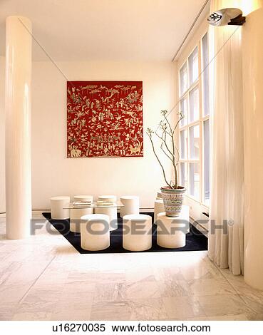 Stock Photography - Circular white stools on black rug in white minimalist eighties dining room with marble floor. Fotosearch