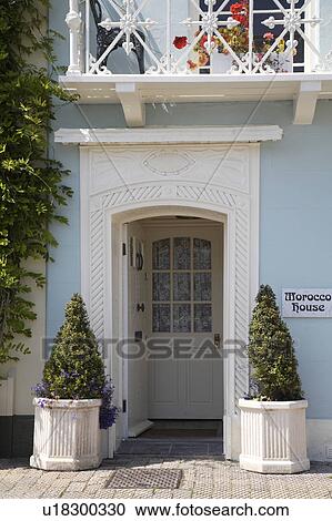 Clipped shrubs in white hexagonal containers on either side of carved white painted doorway with inner front door View Large Photo Image Stock Image - Clipped shrubs in white hexagonal containers on either side of carved white painted doorway with inner front door . Fotosearch