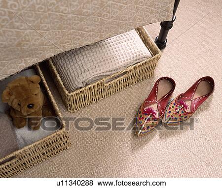 Stock Photo - Close up of a pair of Indian leather shoes beside sea grass baskets under bed of a modern bedroom . Fotosearch