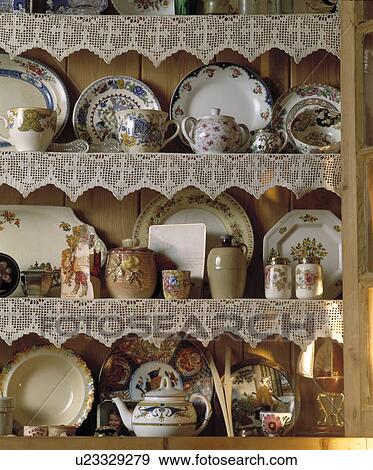 Close up of antique china plates and teapots on pine shelves with lace edging View Large Photo Image Stock Photo - Close up of antique china plates and teapots on pine shelves with lace edging. Fotosearch