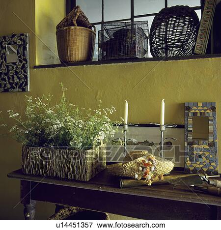Close-up of basket of flowers and candles on wooden table below yellow wall and interior window View Large Photo Image Stock Photo - Close-up of basket of flowers and candles on wooden table below yellow wall and interior window. Fotosearch