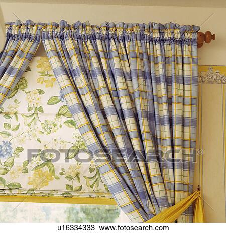 Stock Image - Close-up of blue+yellow checked curtains and yellow floral patterned blind. Fotosearch