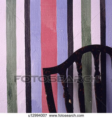 Stock Photo - Close-up of chair against multi-coloured striped wall. Fotosearch