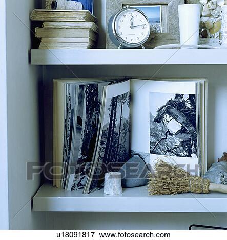Close-up of clock and open book with black and white pictures on white shelves View Large Photo Image Stock Photo - Close-up of clock and open book with black and white pictures on white shelves. Fotosearch