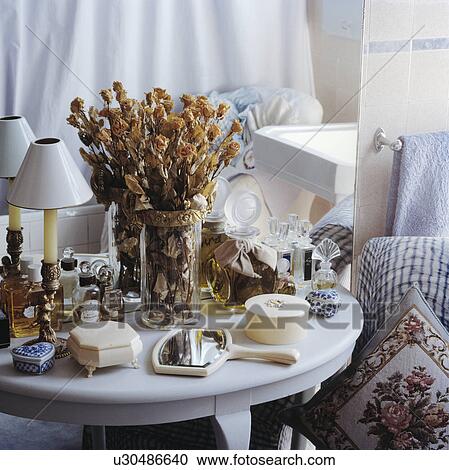 Close-up of dried roses in vase on white table with collection of glass perfume bottles and ivory boxes View Large Photo Image Stock Image - Close-up of dried roses in vase on white table with collection of glass perfume bottles and ivory boxes. Fotosearch
