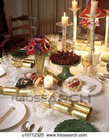 Close-up of gold crackers and candles in tall candlesticks with place settings on Christmas table View Large Photo Image Stock Image - Close-up of gold crackers and candles in tall candlesticks with place settings on Christmas table. Fotosearch