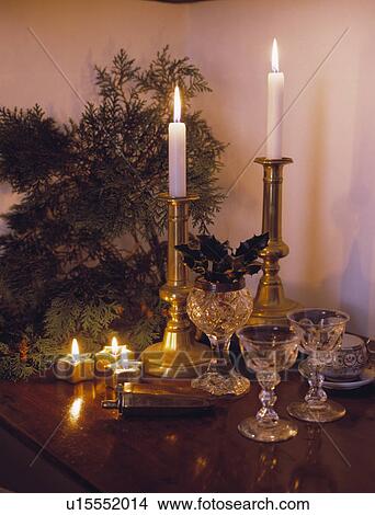 Close up of lighted candles in brass candlesticks with crystal wineclasses and star candles in front of conifer branch View Large Photo Image Picture - Close up of lighted candles in brass candlesticks with crystal wineclasses and star candles in front of conifer branch. Fotosearch