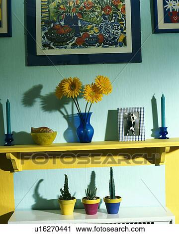 Close-up of orange gerberas in blue vase on yellow shelf above three small cacti in colourful pots View Large Photo Image Stock Image - Close-up of orange gerberas in blue vase on yellow shelf above three small cacti in colourful pots. Fotosearch