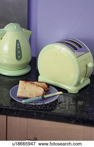 Stock Photo - Close-up of pastel green plastic kettle and maching electric toaster with plate of toast against purple wall. Fotosearch