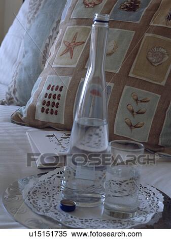 Close-up of tray with water glass and bottle on bed with patterned cushions View Large Photo Image Stock Photography - Close-up of tray with water glass and bottle on bed with patterned cushions. Fotosearch