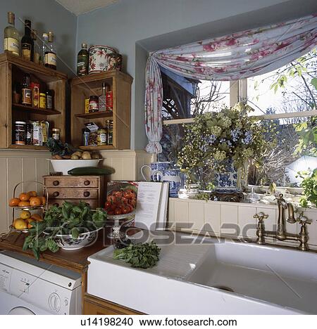 Stock Image - Close-up of white ceramic sink below kitchen window. Fotosearch