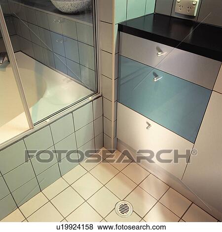 Close-up of white tiled floor with drain below grey and turquoise storage drawers in modern bathroom View Large Photo Image Stock Photo - Close-up of white tiled floor with drain below grey and turquoise storage drawers in modern bathroom. Fotosearch