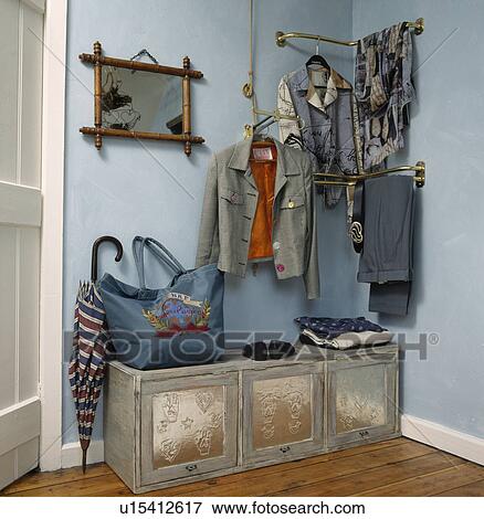 Stock Photo - Clothes stored on rails above grey metal storage unit in pastel blue bedroom. Fotosearch