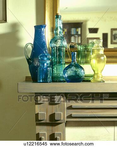Stock Photography - Collection of blue and green glass vases and jugs on wooden mantelpiece. Fotosearch