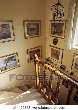 Collection of pictures on neutral walls of staircase with wooden bannisters and cream carpet View Large Photo Image Stock Photo - Collection of pictures on neutral walls of staircase with wooden bannisters and cream carpet. Fotosearch