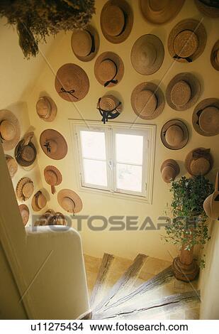 Collection of straw hats on wall above curved stone staircase in French country cottage View Large Photo Image Picture - Collection of straw hats on wall above curved stone staircase in French country cottage. Fotosearch