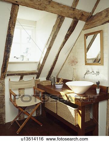 Contemporary basin unit and folding chair in white beamed bathroom under eaves of a period conversion View Large Photo Image Stock Photograph - Contemporary basin unit and folding chair in white beamed bathroom under eaves of a period conversion. Fotosearch