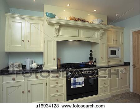 Stock Photo - Contemporary pastel turquoise kitchen with range oven and cream fitted cupboards with black granite worktops. Fotosearch