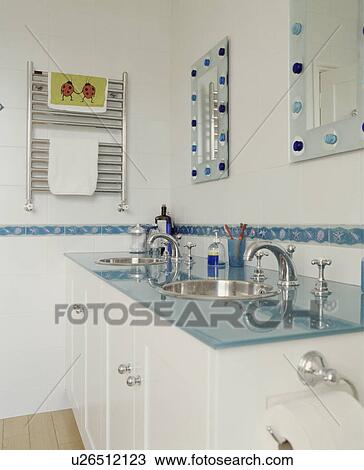 Stock Image - Contemporary white bathroom with stainless steel basins and blue glass topped surface . Fotosearch