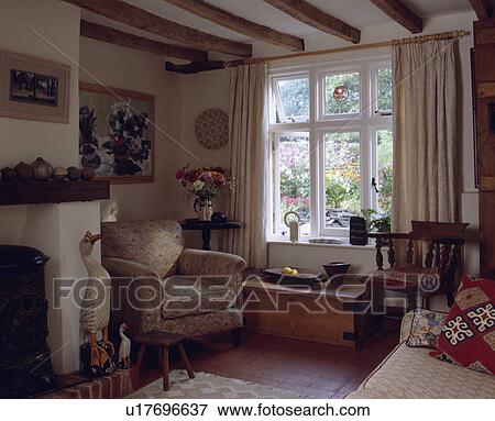 Stock Photo - Cream armchair in traditional cottage living room. Fotosearch