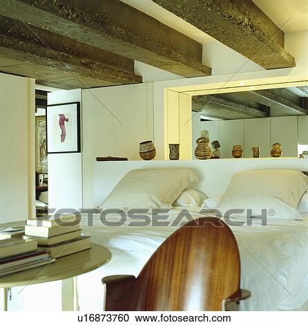 Cream linen pillows on bed with white bedcover in modern white cottage bedroom with large wooden ceiling beams View Large Photo Image Stock Image - Cream linen pillows on bed with white bedcover in modern white cottage bedroom with large wooden ceiling beams. Fotosearch