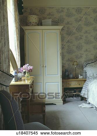 Cream painted wardrobe and patterned pale blue wallpaper in country bedroom with grey carpet View Large Photo Image Stock Photography - Cream painted wardrobe and patterned pale blue wallpaper in country bedroom with grey carpet. Fotosearch