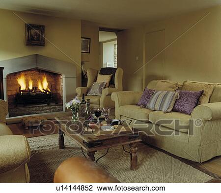 Cream sofa and lighted fire in fireplace in pastel yellow cottage living room View Large Photo Image Stock Image - Cream sofa and lighted fire in fireplace in pastel yellow cottage living room. Fotosearch