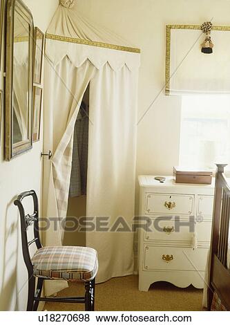 Stock Photo - Cream tented wardrobe in corner of neutral bedroom. Fotosearch