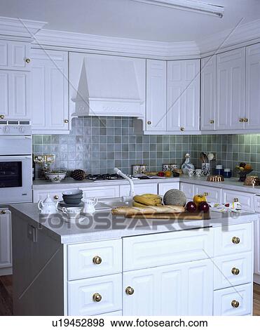 Cups and bread with fruit on island unit in small white kitchen View Large Photo Image Stock Photo - Cups and bread with fruit on island unit in small white kitchen. Fotosearch