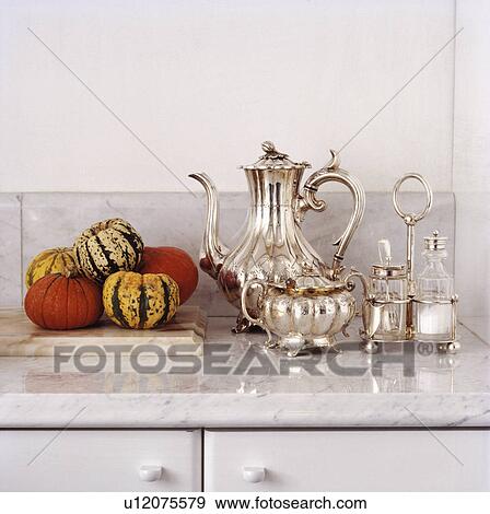 Stock Photo - Detail shot showing silver teaset and decorative gourds on marble top.. Fotosearch