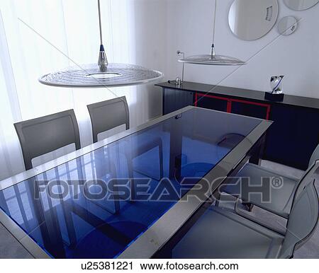 Disc lights above blue glass and steel table in modern white eighties dining room View Large Photo Image Stock Image - Disc lights above blue glass and steel table in modern white eighties dining room. Fotosearch