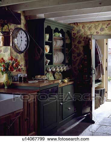 Dishwasher and green dresser in cottage kitchen with fruit-patterned wallpaper and white ceiling beams View Large Photo Image Stock Photo - Dishwasher and green dresser in cottage kitchen with fruit-patterned wallpaper and white ceiling beams. Fotosearch