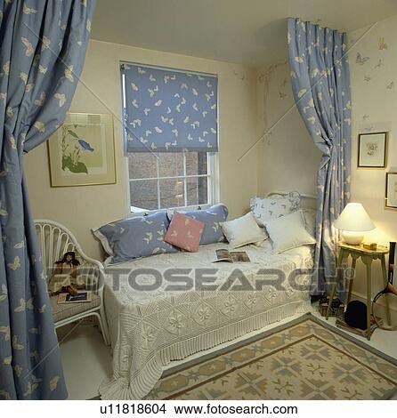 Divan bed with crochet cover in front of butterfly-patterned blue blind at window and matching curtains screening bed View Large Photo Image Picture - Divan bed with crochet cover in front of butterfly-patterned blue blind at window and matching curtains screening bed. Fotosearch