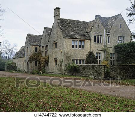 Stock Image - Exterior of large stone detached country house with drive or road in front and walled garden.. Fotosearch