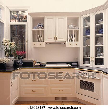 Fitted plate rack above white hob in black worktop in small white kitchen with white oven View Large Photo Image Stock Photo - Fitted plate rack above white hob in black worktop in small white kitchen with white oven. Fotosearch