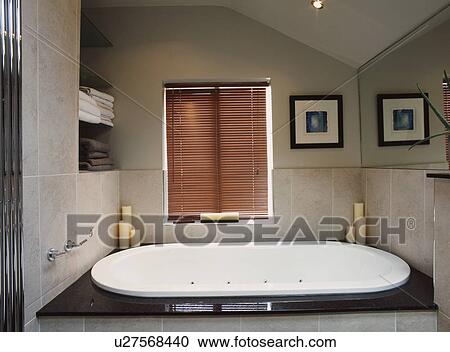 Stock Image - Fitted whirlpool bath in a modern tiled bathroom . Fotosearch