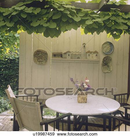 Stock Photo - Furniture on patio in country garden in summer. Fotosearch