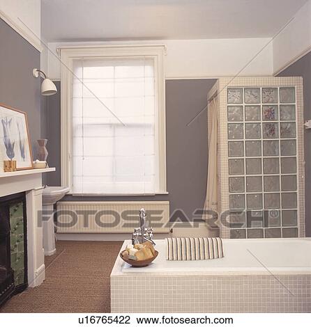 Glass brick shower wall amd white bath in modern grey bathroom with white blind and sisal carpet View Large Photo Image Stock Image - Glass brick shower wall amd white bath in modern grey bathroom with white blind and sisal carpet. Fotosearch