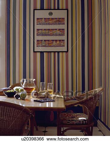 Glass jug on table with wicker chairs in small dining room with multicoloured striped wallpaper View Large Photo Image Stock Photograph - Glass jug on table with wicker chairs in small dining room with multicoloured striped wallpaper. Fotosearch