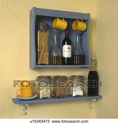 Glass storage jars and wine carafes on blue shelves with yellow cups on hooks View Large Photo Image Stock Image - Glass storage jars and wine carafes on blue shelves with yellow cups on hooks. Fotosearch