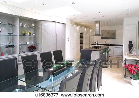 Glass table and upholstered black chairs in modern openplan white kitchen and dining room View Large Photo Image Stock Photo - Glass table and upholstered black chairs in modern openplan white kitchen and dining room. Fotosearch